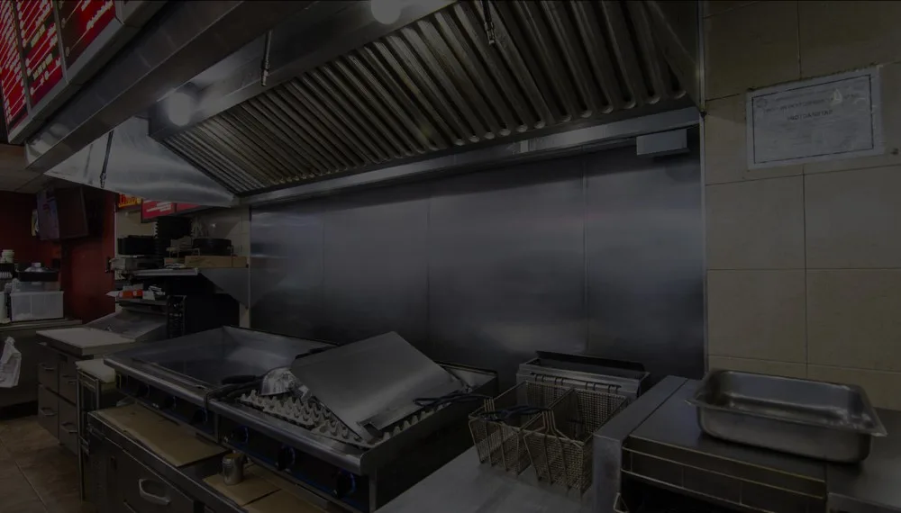 Restaurant cooking line under a stainless steel exhaust hood with fryers and griddle
